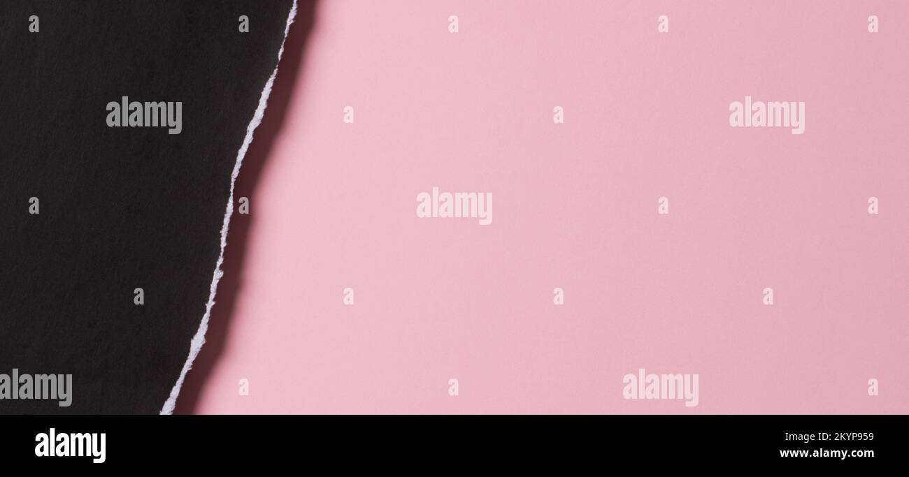 Schwarzer Grunge gerissenes Papierstück mit zerkleinerter Kante auf pastellrosafarbenem Papierhintergrund. Draufsicht, Kopierbereich Stockfoto
