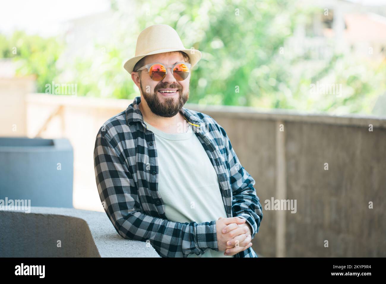 Ein bärtiges Männerporträt in Sommerkleidung und Hut steht über dem Straßen-Stadt- und Reisekonzept Stockfoto