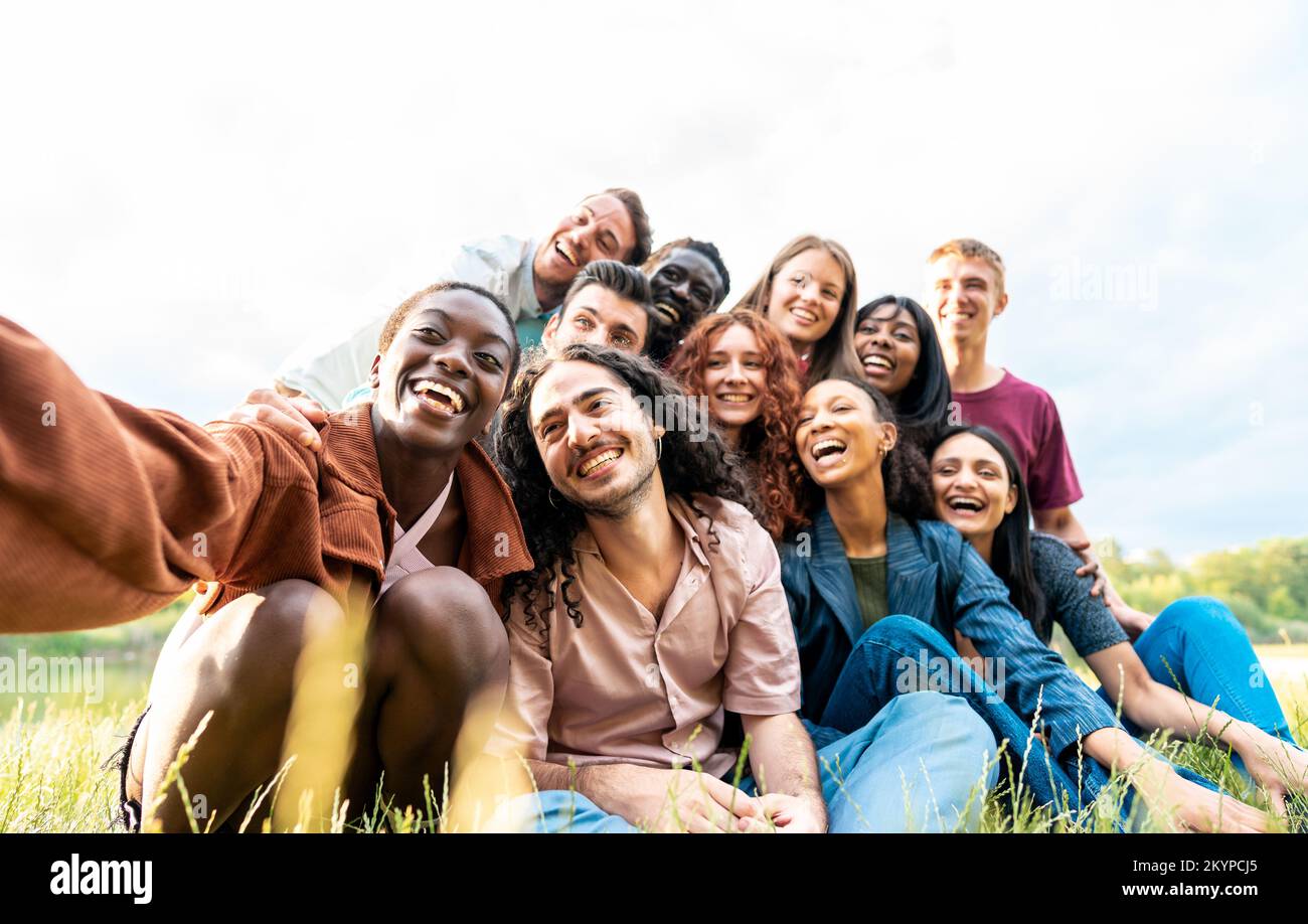 Eine junge afrikanische Frau macht ein Selfies seiner internationalen Freunde während eines Picknickens Stockfoto