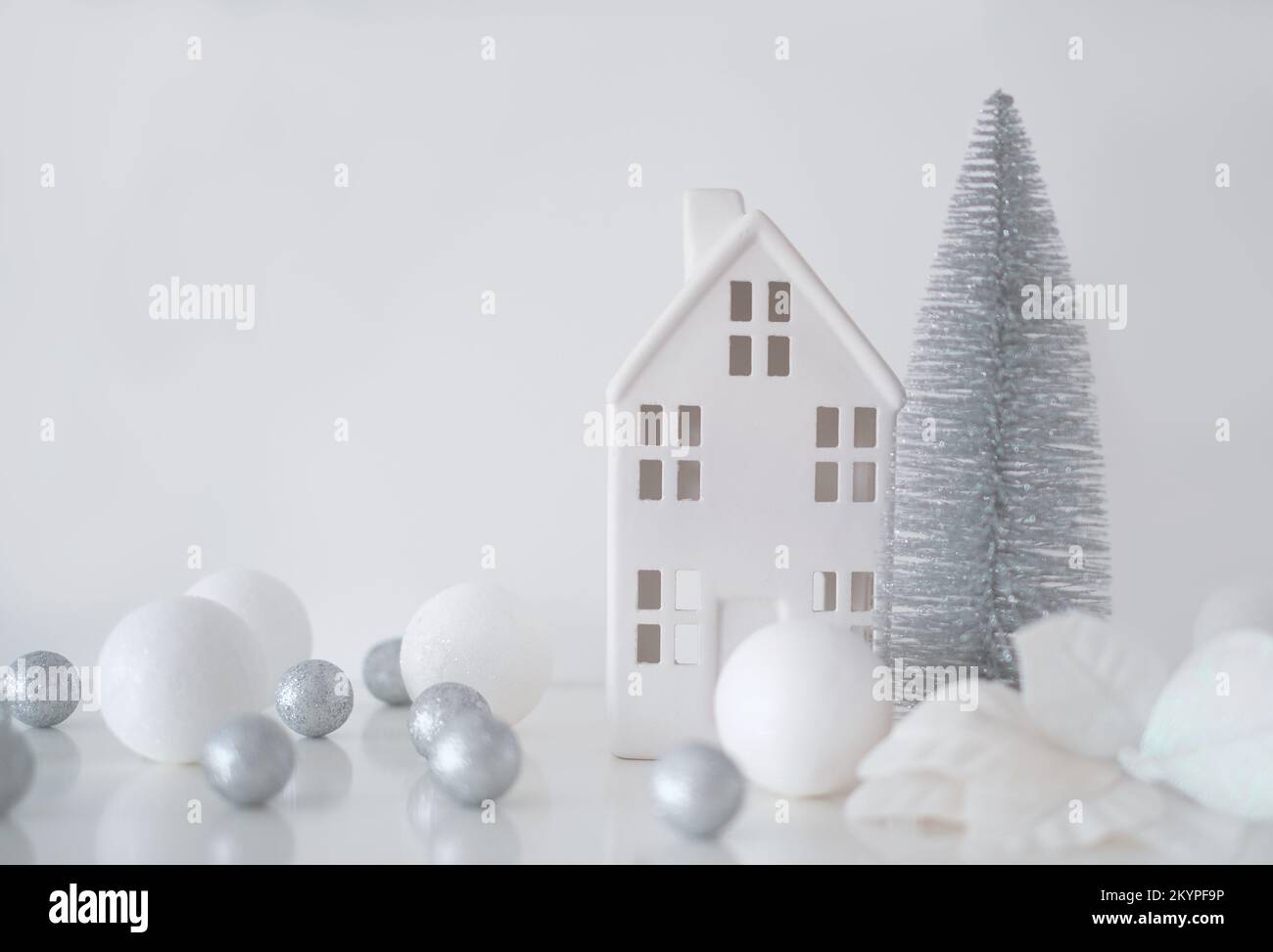 Weihnachtskomposition. Weihnachtskugeln weiß und silber, dekoratives Haus, weihnachtsbaum auf weißem Hintergrund Stockfoto