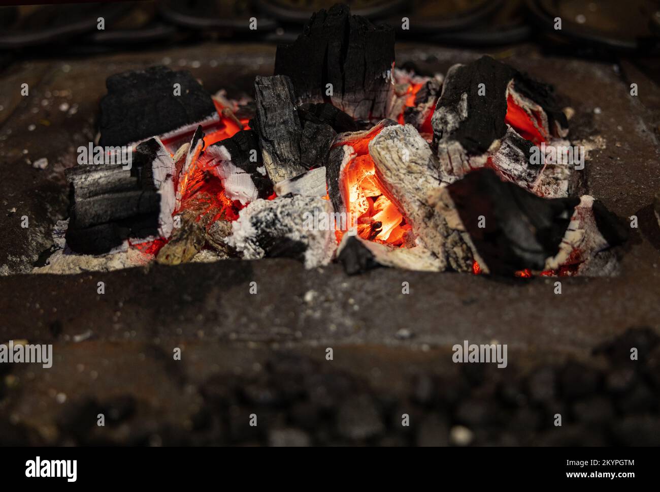Malerische brennende, helle Kohlen schwelen in einem Metallständer Stockfoto