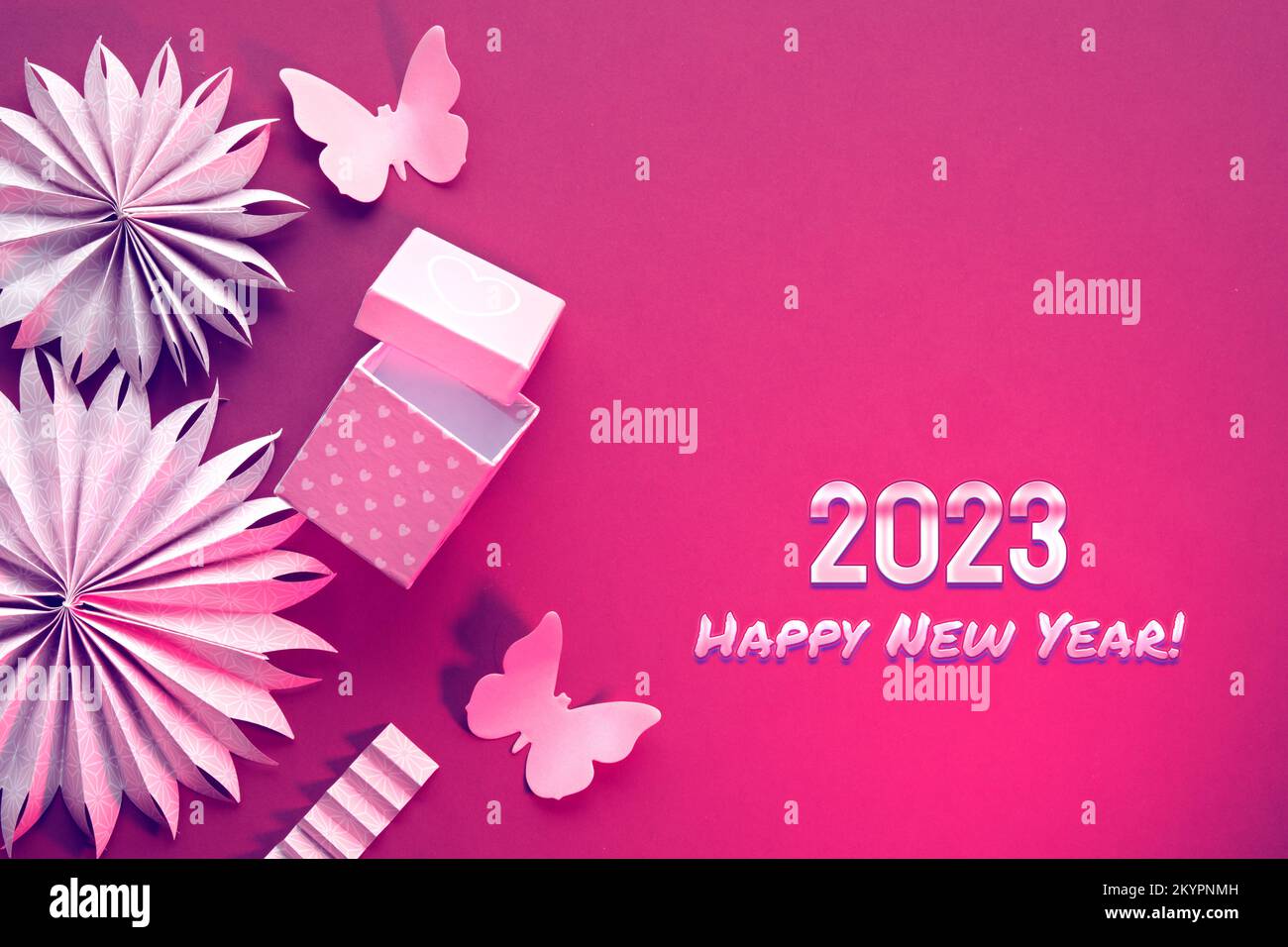 Text 2023 Frohes neues Jahr. Papierfächer, Schmetterlinge, Blumen und Schmetterlinge. Flach liegend mit Papierornamenten, Dekorationen, Geschenkbox auf leuchtendem Magenta Stockfoto