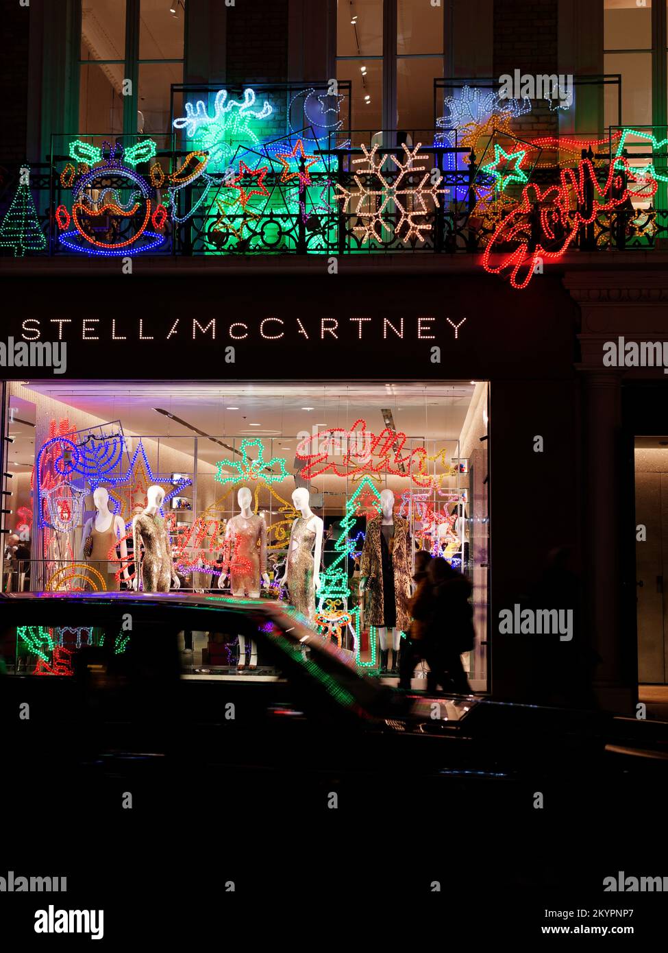 Stella McCartney berühmter Modeladen Weihnachten Schauen Sie, wie ein Auto unscharf durch Bewegung an der Old Bond Street, London vorbeifährt. Stockfoto