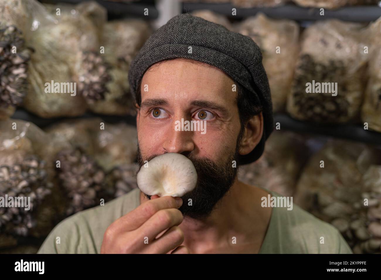 Nahaufnahme eines jungen Bauern, der einen Pilz schnüffelt Stockfoto