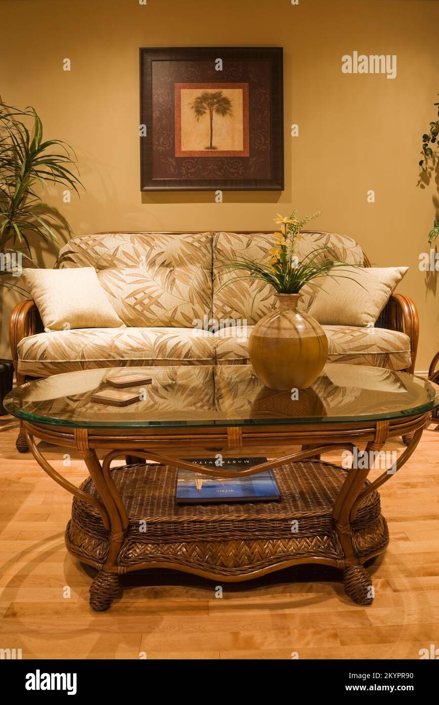 Couchtisch mit Glasplatte und Korbsofa im Wohnzimmer in einem kleinen Bungalow-Stil Haus. Stockfoto