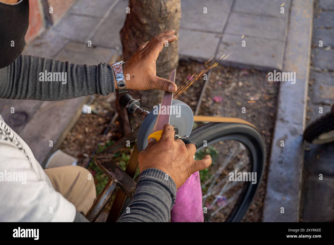 Ein Messer schärfender Straßenverkäufer, der ein Messer am Straßenrand in Oaxaca City, Mexiko, hakt Stockfoto