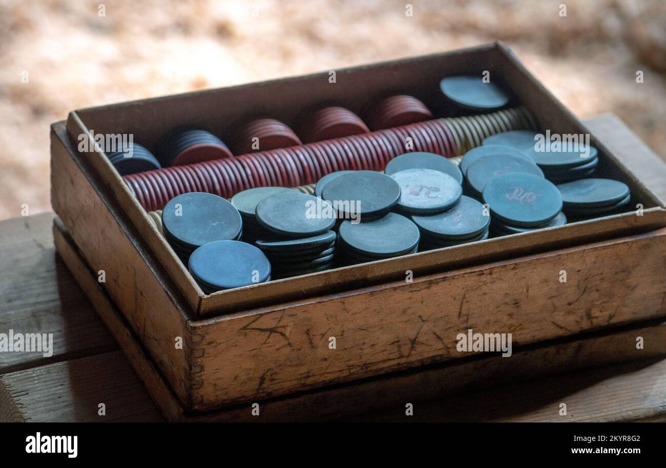 Eine alte, antike Holzkiste enthält Dutzende von Retro-Poker-Chips aus den 1800er Jahren Stockfoto