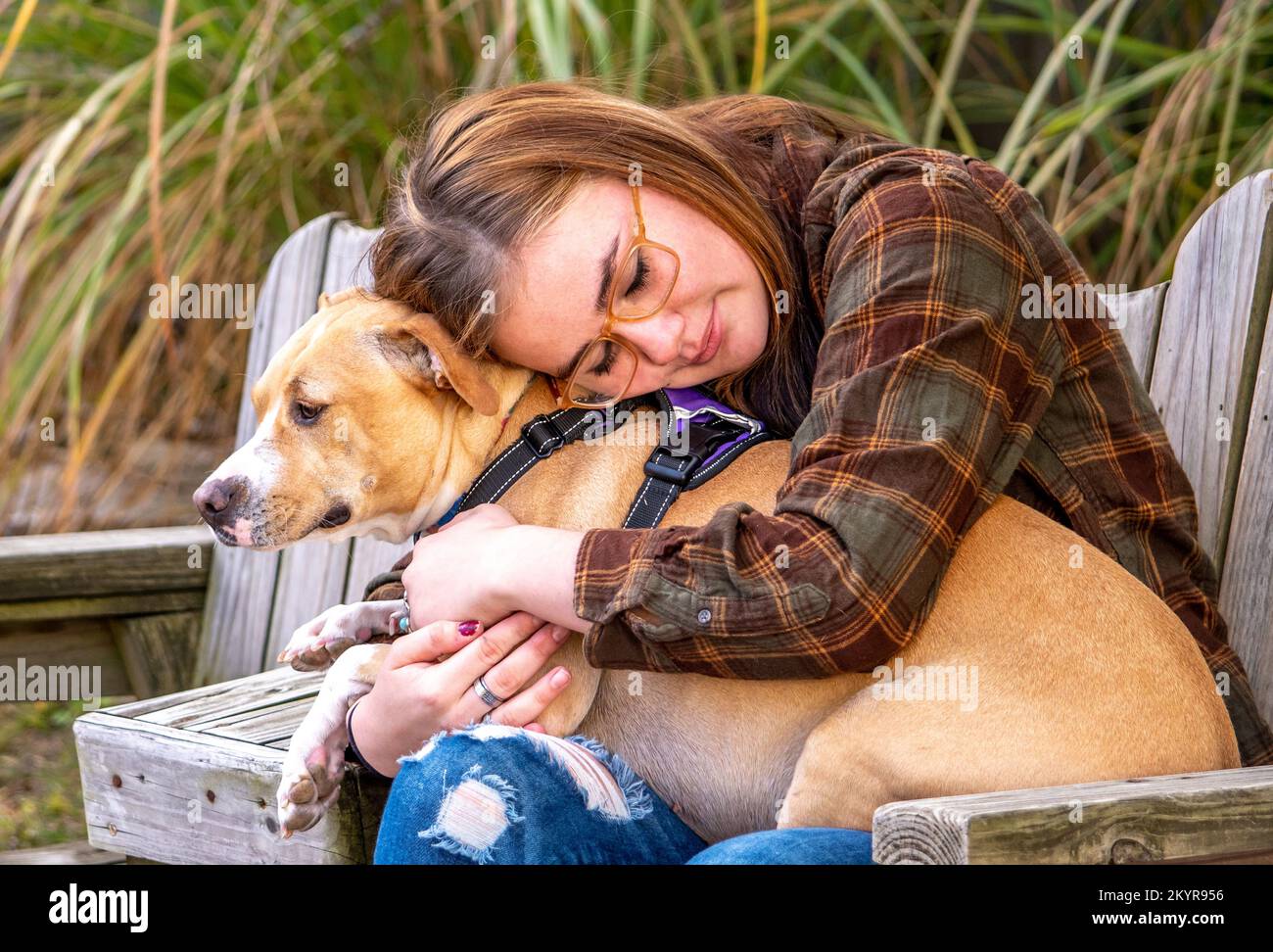 Ein junges Mädchen mit Epilepsie umarmt ihren Anfallshund, eine ganz besondere Begleiterin Stockfoto