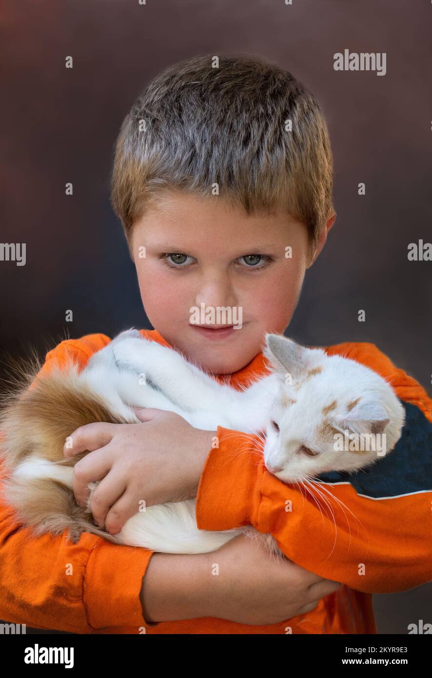 Der süße Junge hält eine große weiße Katze, sein Lieblingstier Stockfoto