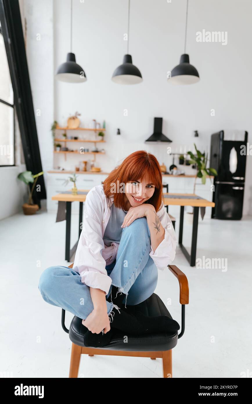Frau sitzt auf einem Stuhl in einer modernen Küche Stockfoto