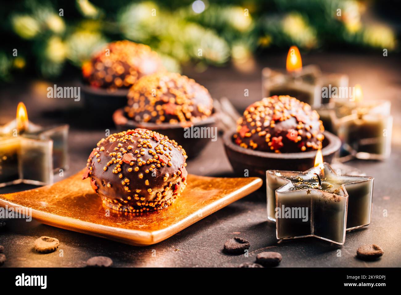 Kleine Schokoladenkuchen zu Weihnachten mit Kerzen und Ziergegenständen Stockfoto