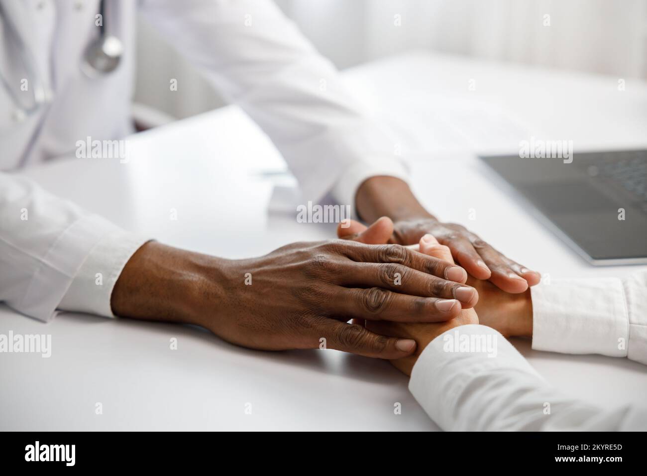 Ein afroamerikanischer Arzt tröstet eine Frau bei einem Empfang in seinem Büro. Medizinische Unterstützung. Die Arztberatung. Helfen Sie dem Patienten. Stockfoto
