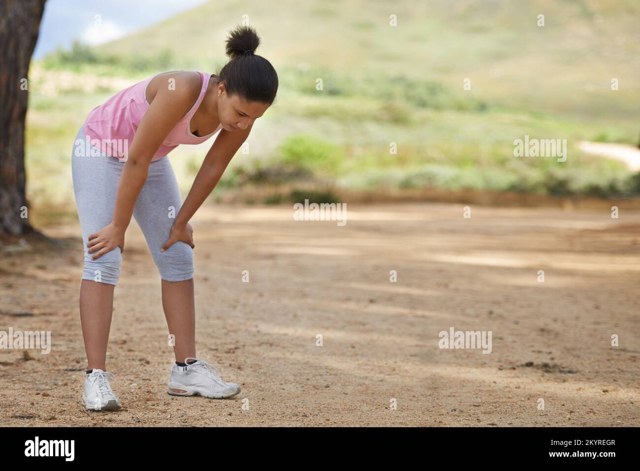 Sie hat es geschafft. Eine junge Frau, die nach einem Lauf nach Luft schnappt, mit den Händen auf den Knien. Stockfoto