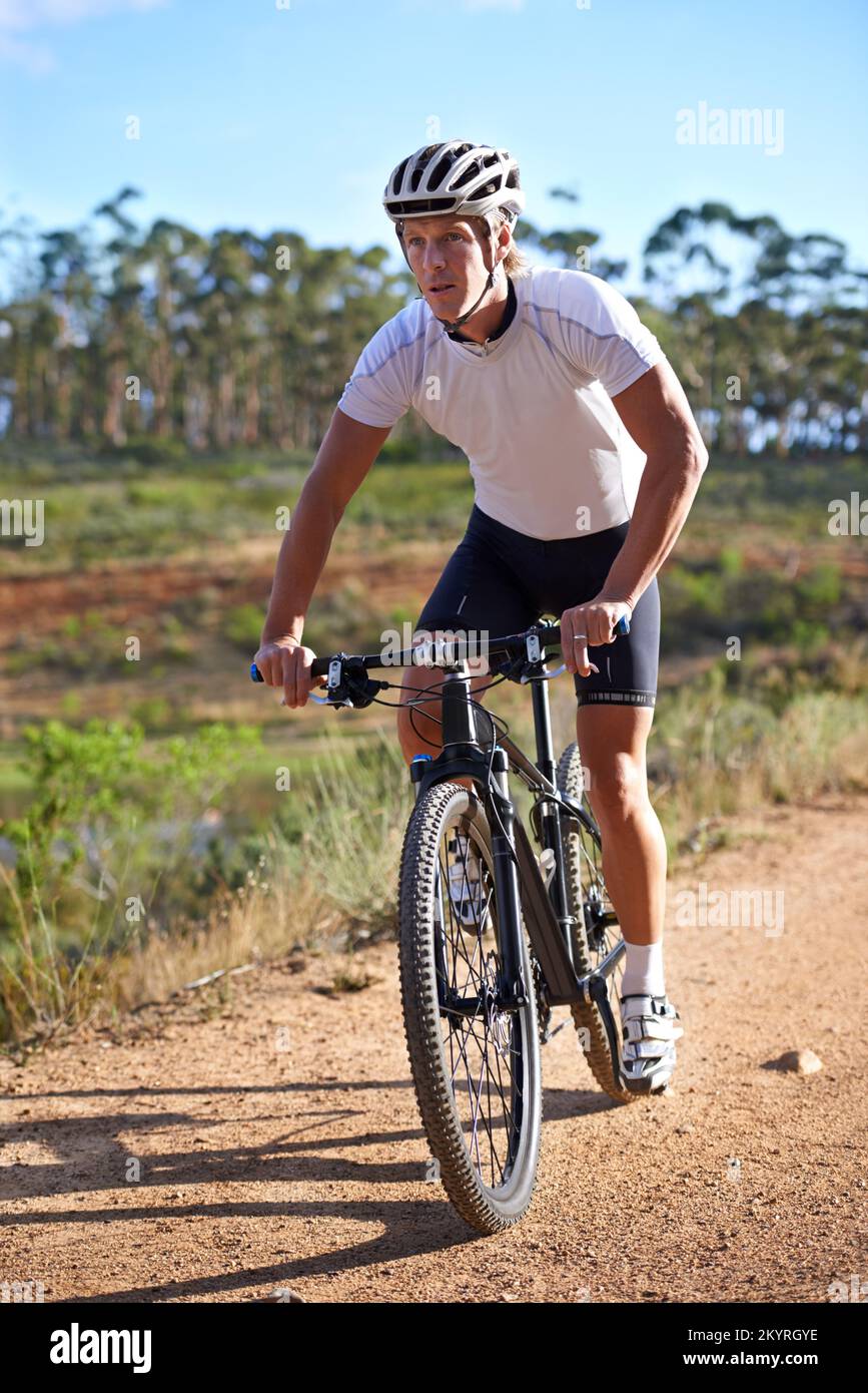Dominiere die Pfade. Ein junger Mann, der mit seinem Mountainbike auf einem Waldweg fährt. Stockfoto