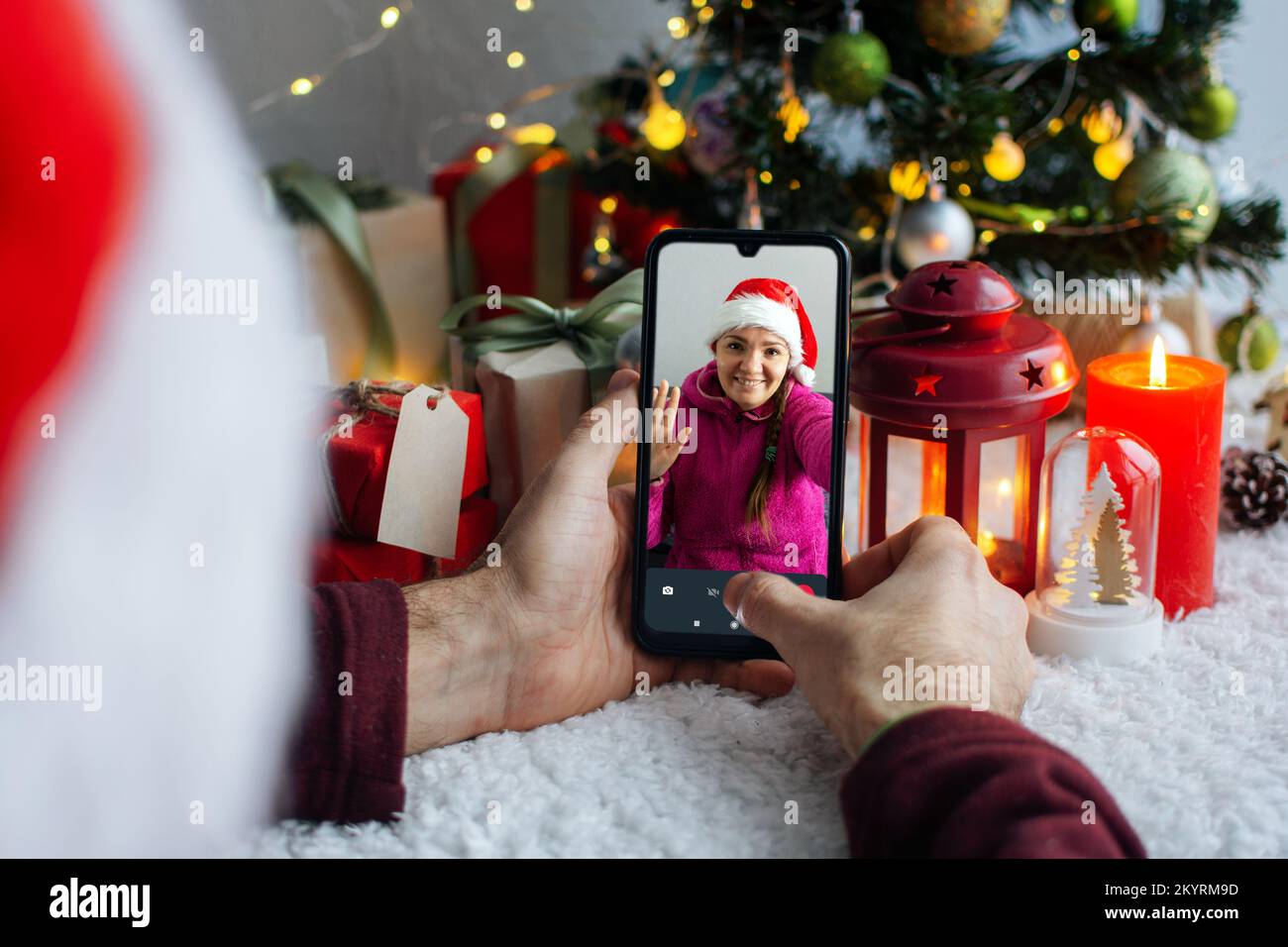 Videoanrufe an Freunde am Heiligabend. Ein Mann ruft Verwandte und Freunde über ein Smartphone an. Das Mädchen nahm den Videoanruf entgegen und winkte mit der Hand. Im Stockfoto