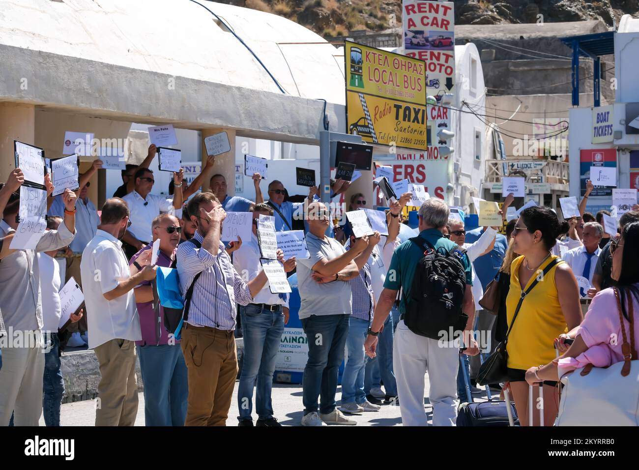 Santorin, Griechenland - 16. September 2022 : Ansicht von Personen mit Schildern mit Namen von Touristen, die Transferdienste im Hafen von Santorin gebucht haben Stockfoto