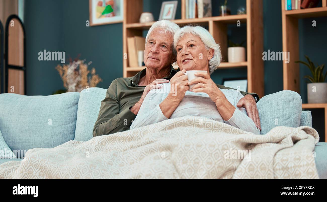 Entspannen, lieben und Kaffee mit dem alten Paar auf dem Sofa mit Decke zum Kuscheln, liebevoll oder Fernsehen. Gemütlich, komfortabel und pensioniert mit Mann und Stockfoto