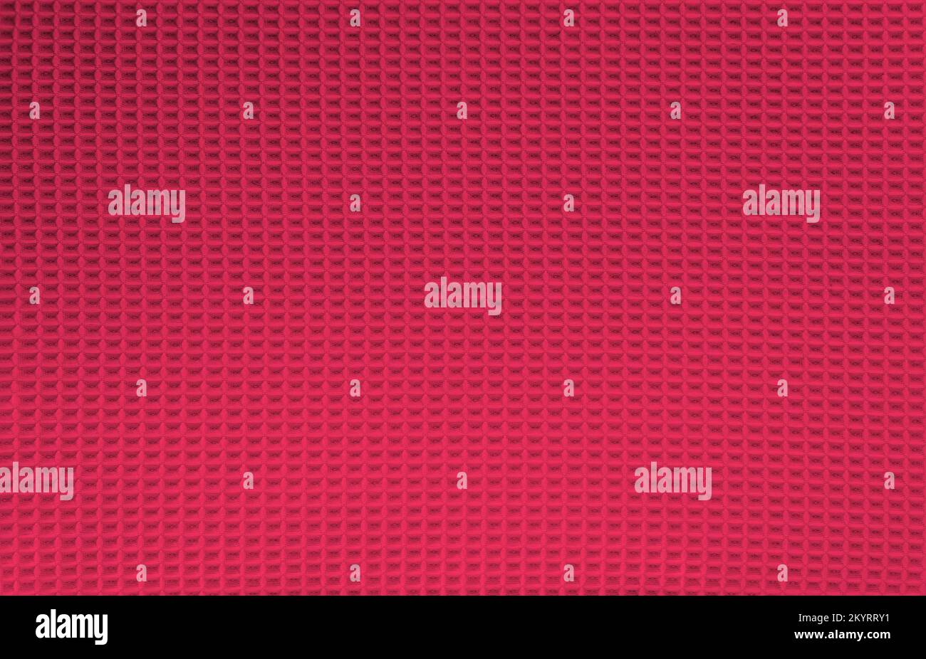 Abstrakter Hintergrund in Viva Magenta. Waffelmuster aus natürlicher Baumwolle, Stoffstruktur. Draufsicht, Nahaufnahme. Farbe des Jahres 2023. Stockfoto