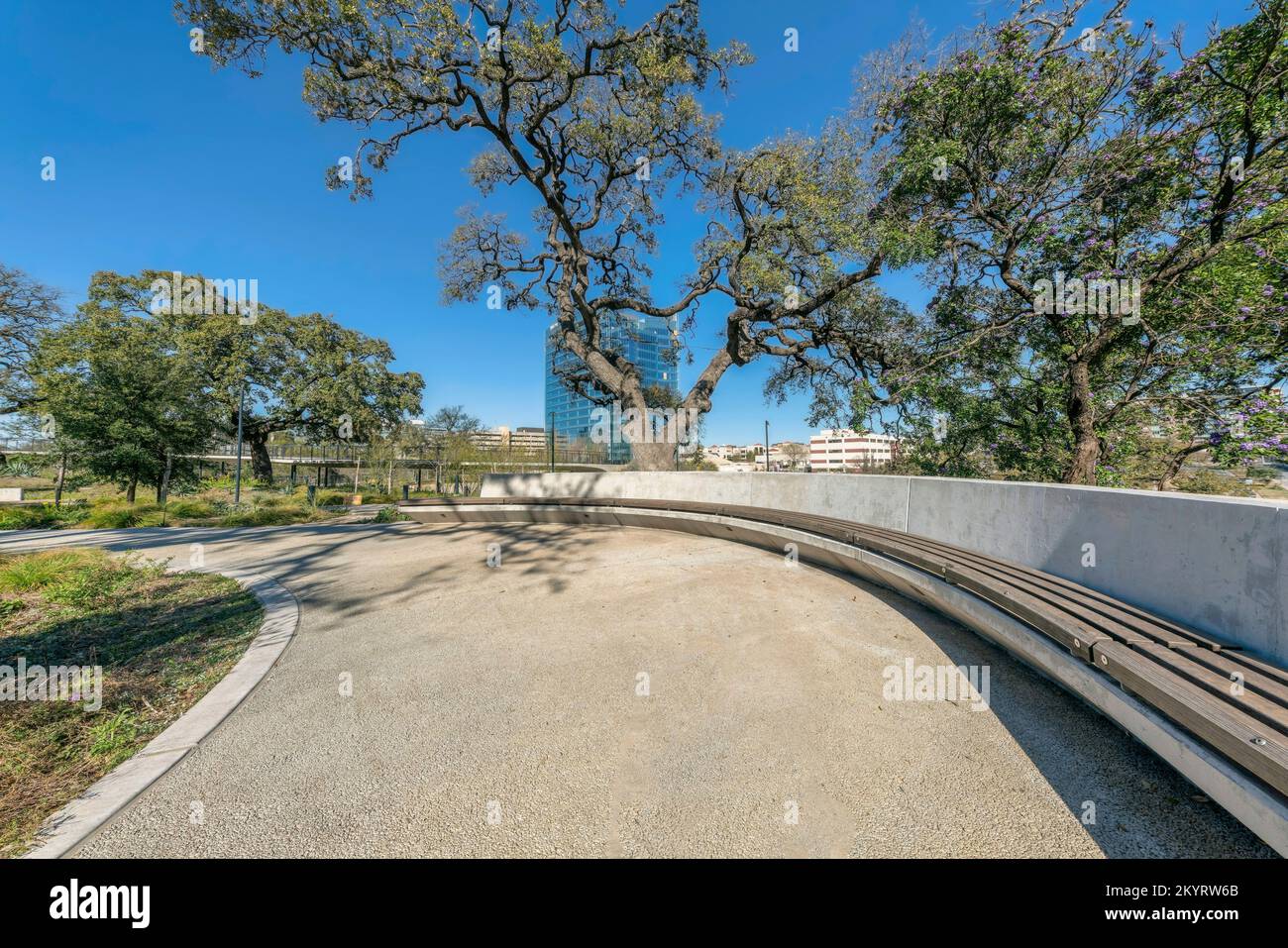 Gepflasterter Wanderweg mit eingebautem Sitz im Waterloo Park in Austin, Texas. Malerische Parklandschaft mit Annehmlichkeiten und Naturlandschaft Stockfoto