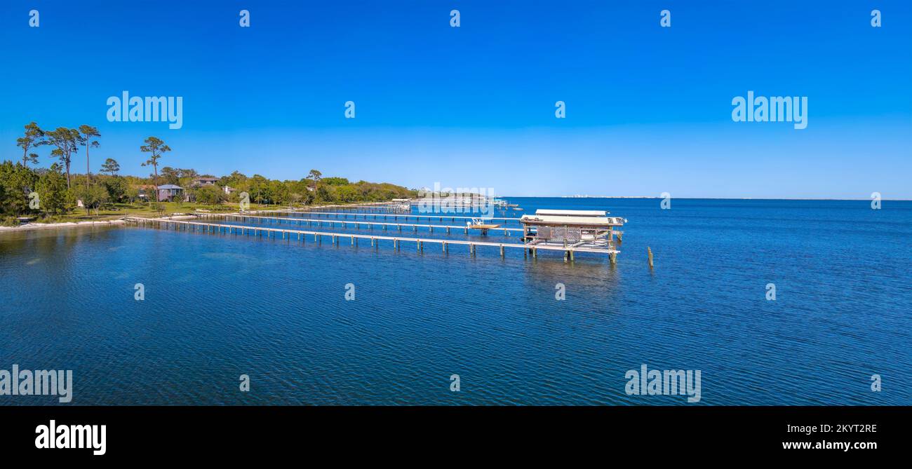 Panoramaaussicht auf die malerische Bucht mit Piers über dem pulsierenden blauen Wasser. Üppig grüne Bäume und Häuser sind am Ufer mit einer klaren blauen Sackgasse zu sehen Stockfoto