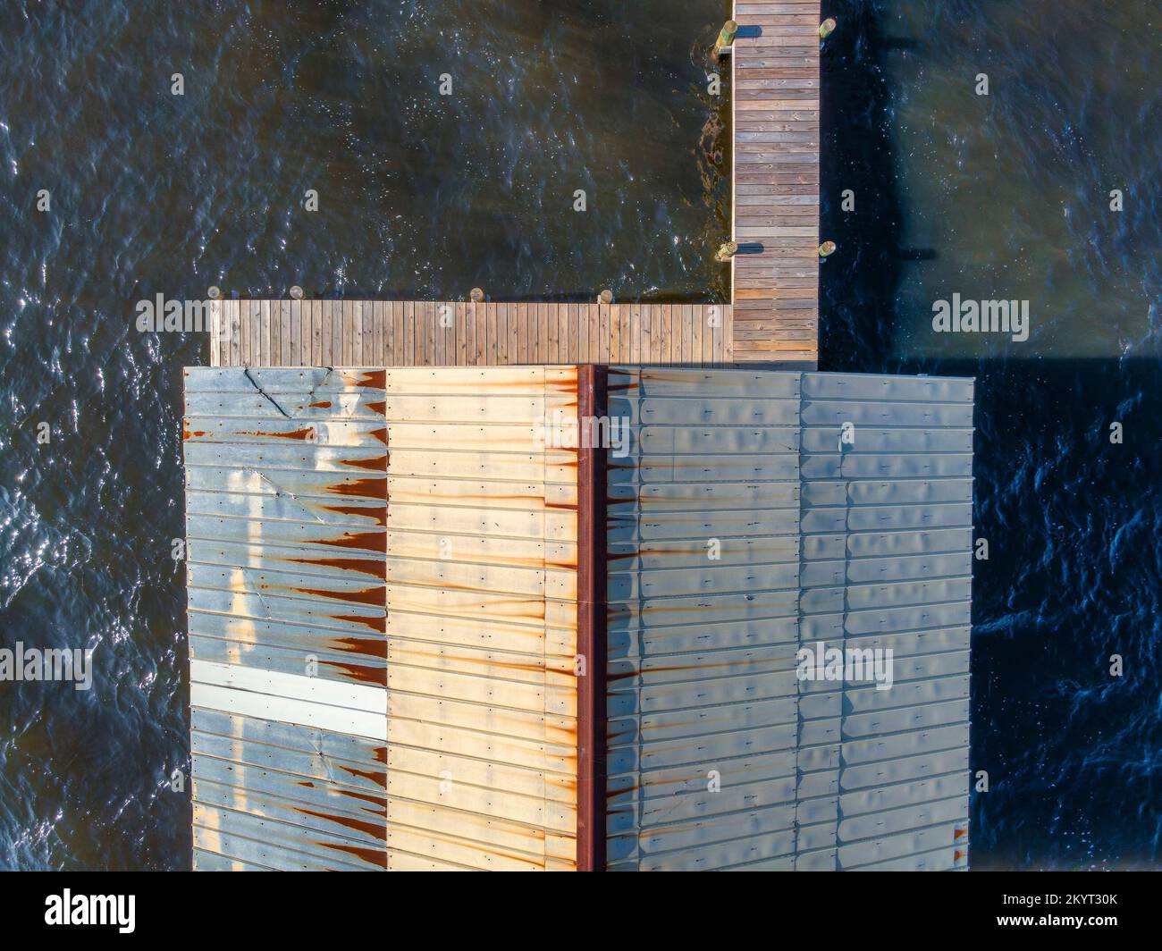 Giebeldach und Pier vor der Salzwasserbucht in Navarre Florida aus der Vogelperspektive. Draufsicht Drohnenaufnahme eines alten Gebäudes und Holzsteg über der Dunkelheit Stockfoto