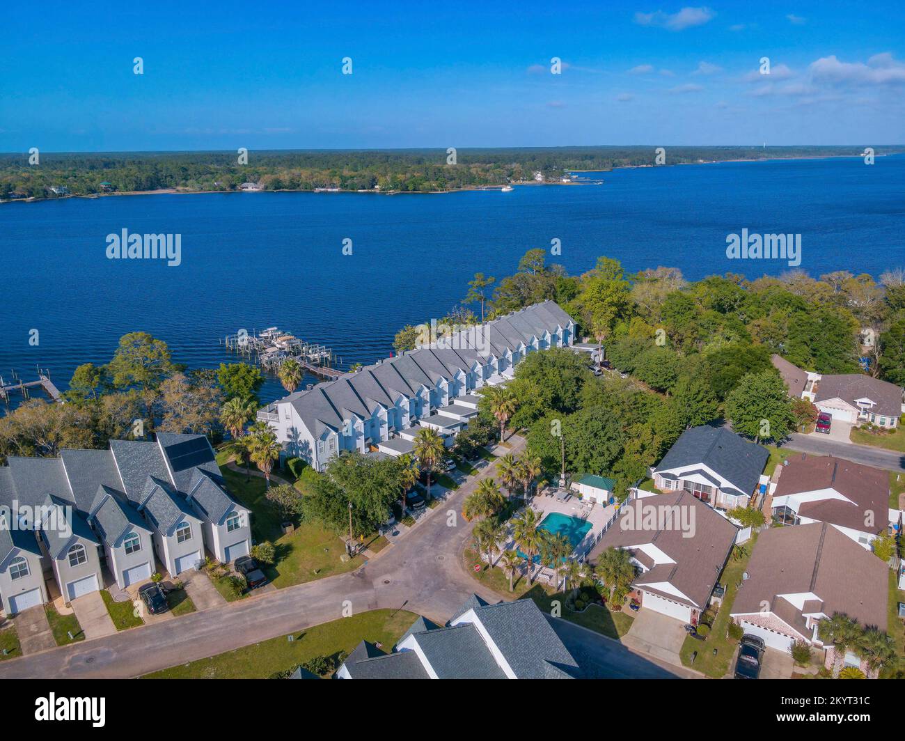 Stadthäuser und Ferienwohnung mit Blick auf die malerische blaue Bucht in Navarre Florida. Luftlandschaft von Wohnhäusern am Ufer vor einem ruhigen Gewässer Stockfoto