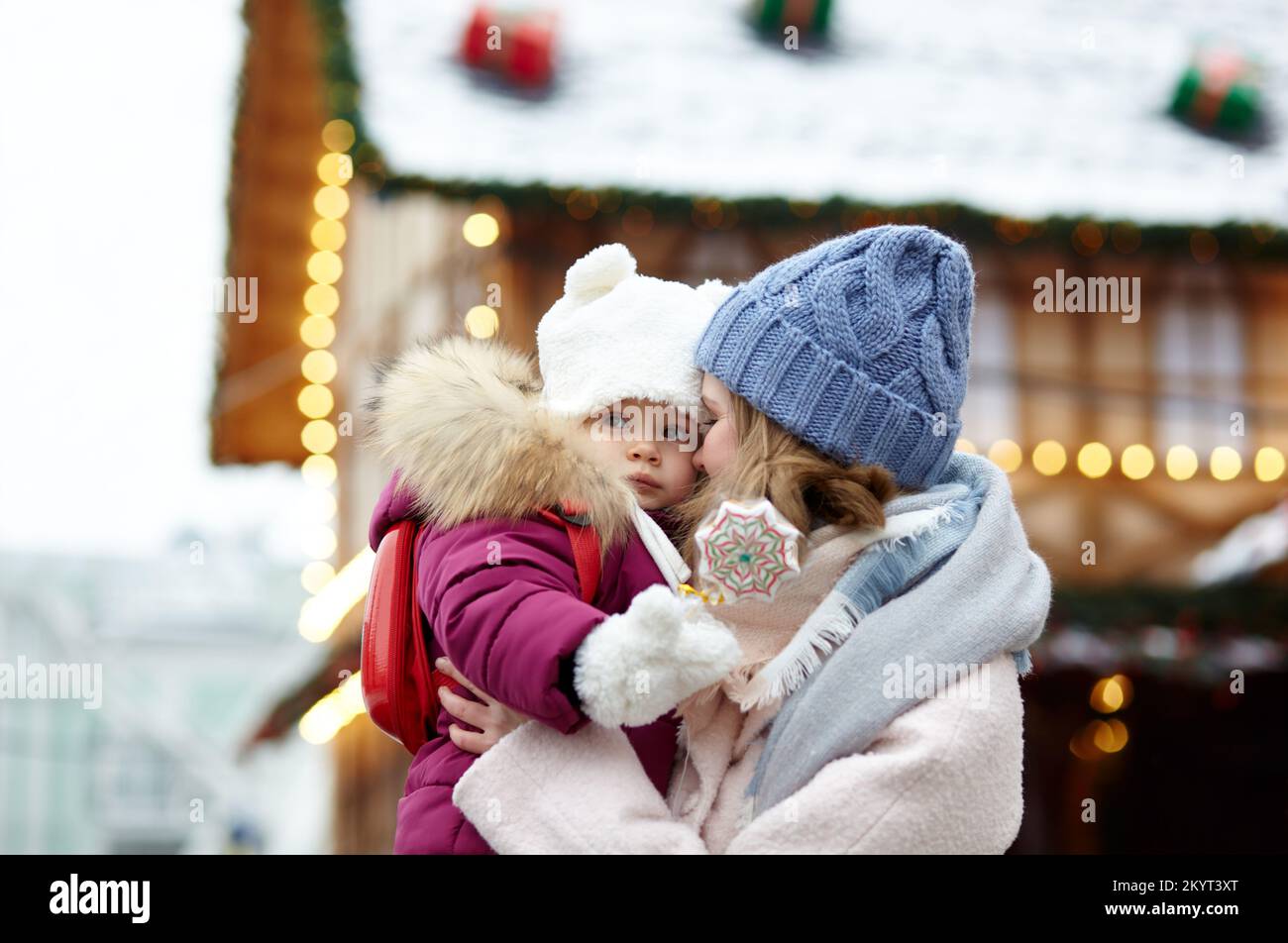 Mutter und Tochter laufen an Weihnachten und Neujahr durch die Stadt. Eltern und kleine Kinder haben Spaß im Freien Stockfoto