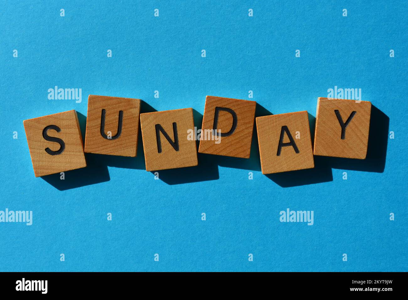 Sonntag, Wort in hölzernen Buchstaben isoliert auf blauem Hintergrund Stockfoto