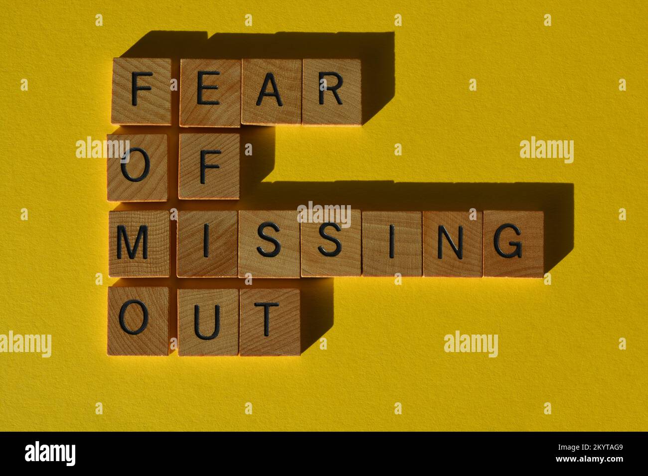 FOMO, Akronym für Angst, etwas zu verpassen, in hölzernen Buchstaben isoliert auf gelbem Hintergrund Stockfoto