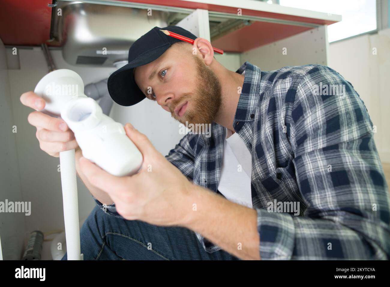 Klempner unter dem Waschbecken in der Küche Stockfoto