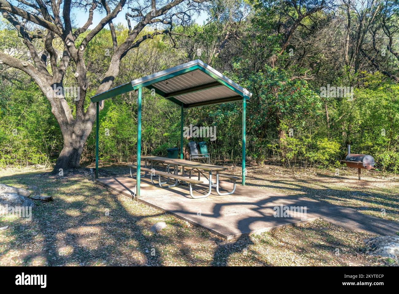 Austin, Texas - Picknicktisch mit Sitzen unter einem Dach in einem Gemeinschaftspark. Essbereich mit Grills auf der rechten Seite gegenüber den Bäumen im Hintergrund. Stockfoto