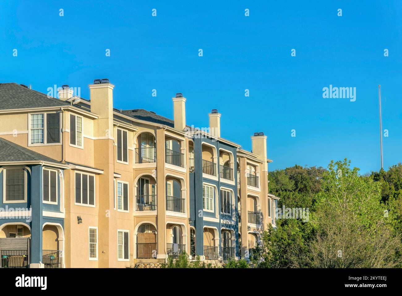 Austin, Texas - Apartmentgebäude in der Nähe des Lake Austin mit blauer und beigefarbener Fassade. Außenansicht eines Wohngebäudes mit Balkonen und Blick auf die Bäume Stockfoto