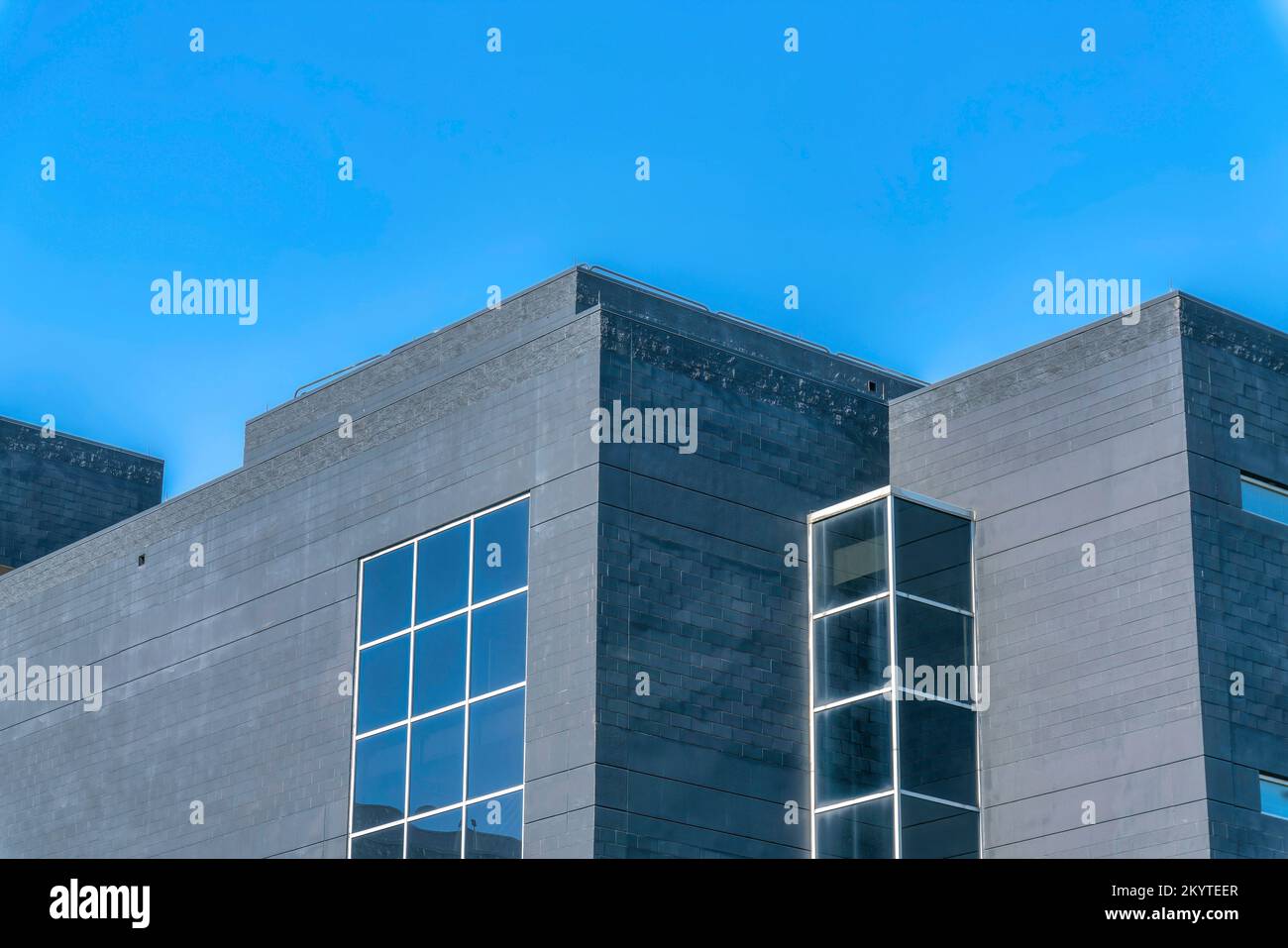 Austin, Texas: Modernes Gebäude mit grauen Betonwänden und Gitterfenstern. Niedriger Winkel mit Blick auf ein flaches Gebäude am blauen Himmel. Stockfoto