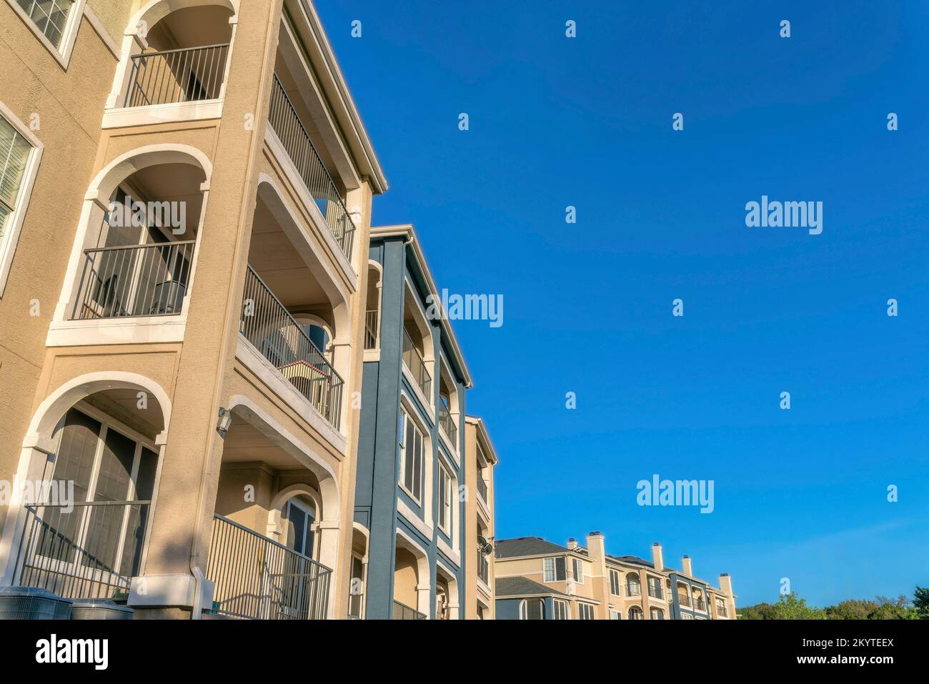 Austin, Texas - Flachblick auf einen Apartmentkomplex mit Balkonen. Außenansicht eines Wohngebäudes mit beigefarbenen, blauen Wänden und weißen Verzierungen. Stockfoto