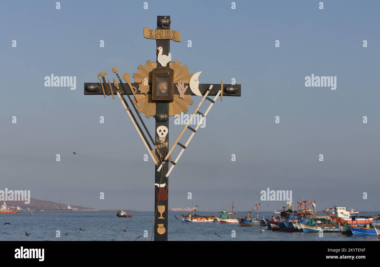 Ein Kreuz mit Darstellungen der Arma Christi, der Waffen Christi oder der Instrumente der Passion, in der Nähe des Fischerboots Pier Paracas. Sym Stockfoto