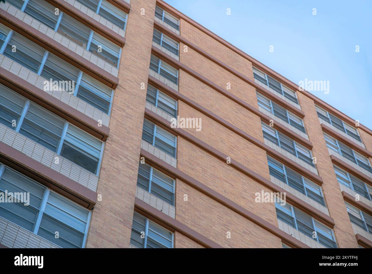 Außenansicht des Gebäudes mit Blick aus einem niedrigen Winkel und braunen Verkleidungen in Austin, Texas. Fassade eines Gebäudes mit braunen Wandfliesen und Geländern an den verglasten Fenstern. Stockfoto