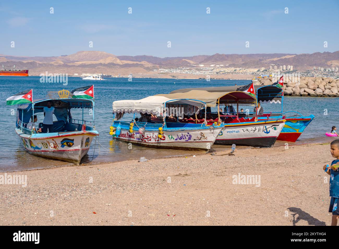 Die Boote fuhren am Al-Ghandour Beach in Aqaba Jordan und blickten auf die Hügel von Isreal und Ägypten Stockfoto
