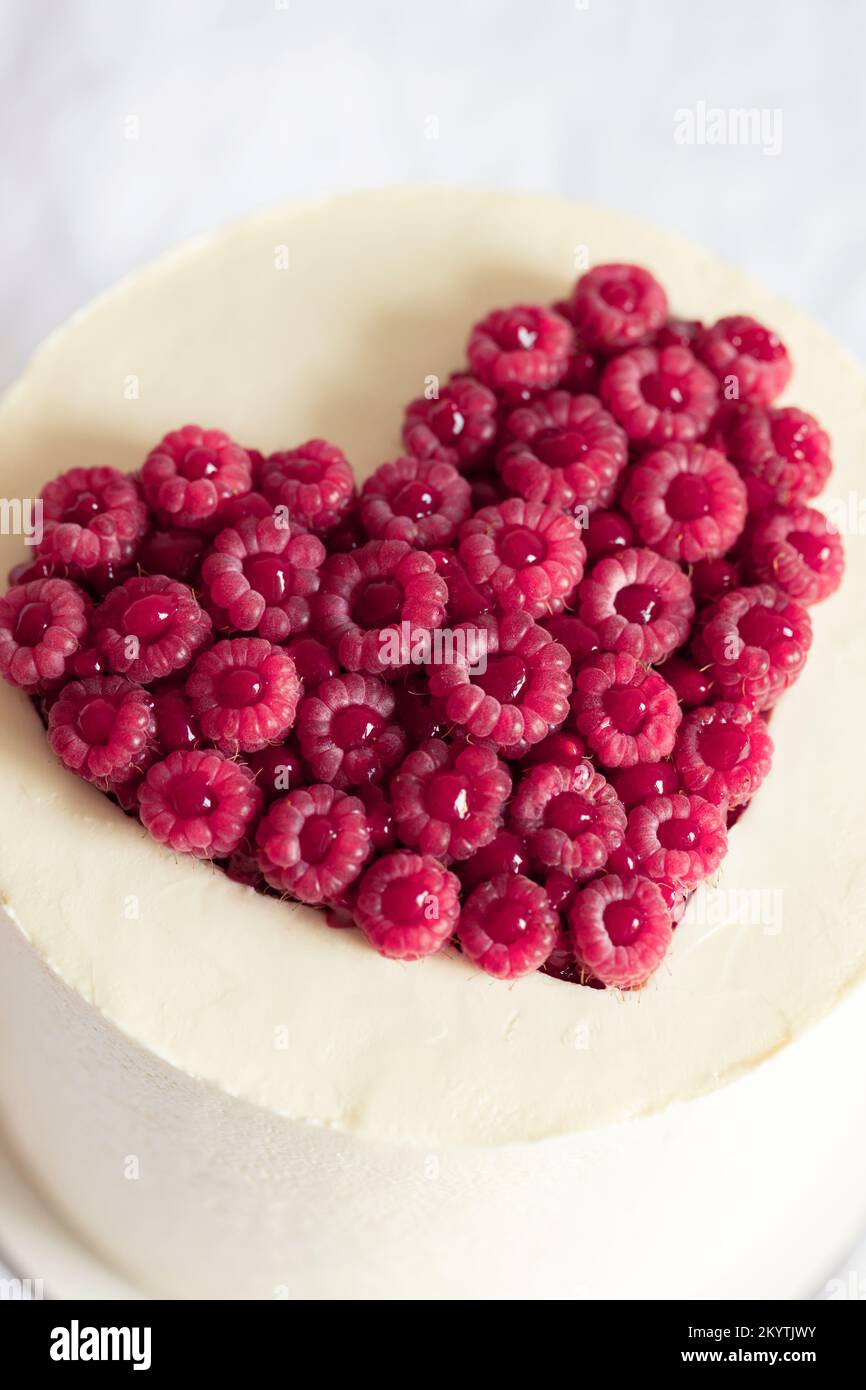 Kuchen mit Himbeer-Viva-Herzdekoration in Magenta. Stockfoto