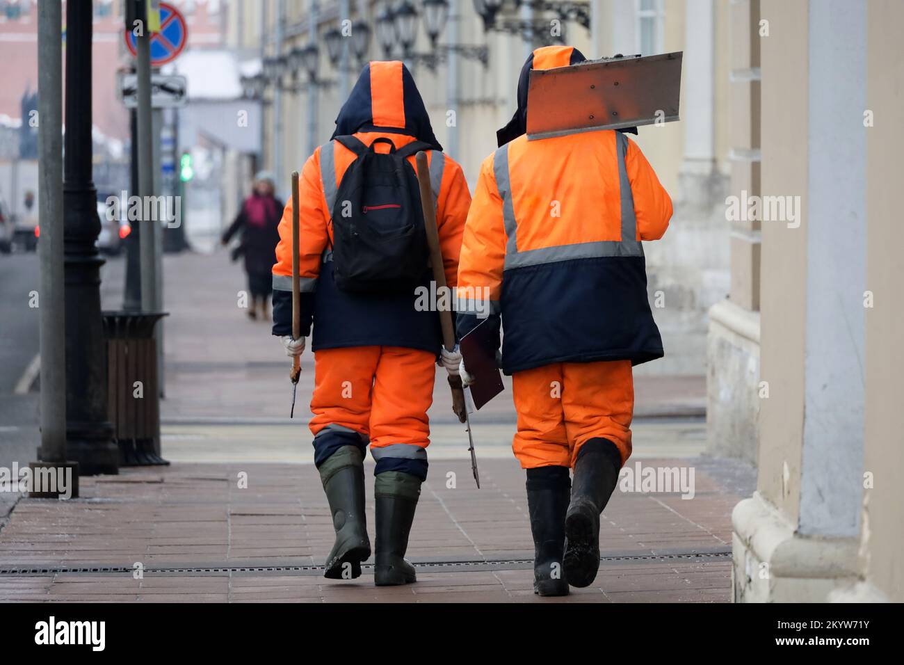Zwei Hausmeister gehen die Straße entlang. Ich putze die Winterstadt, Arbeiter mit Schaufeln Stockfoto