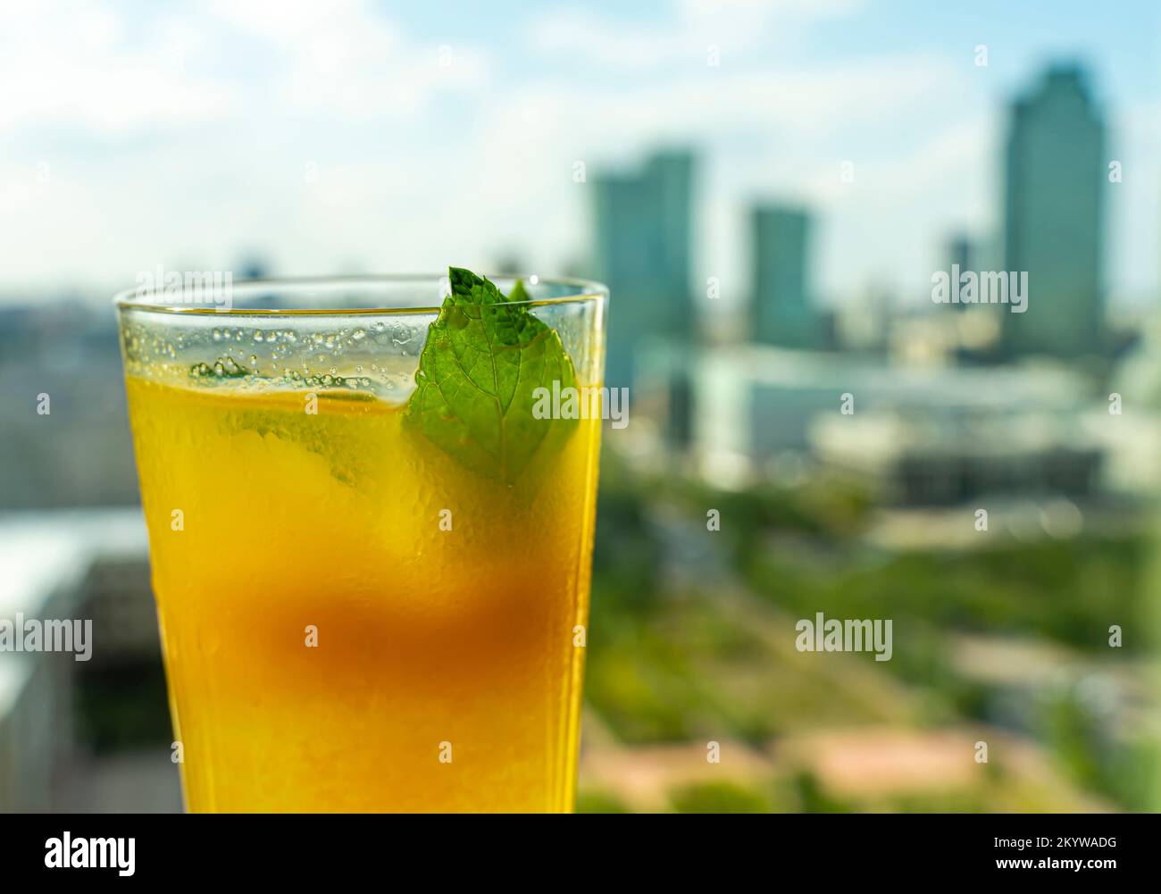 Orangengetränk mit Minzblattwerk und Stadtlandschaft, Wolkenkratzer im Hintergrund Stockfoto