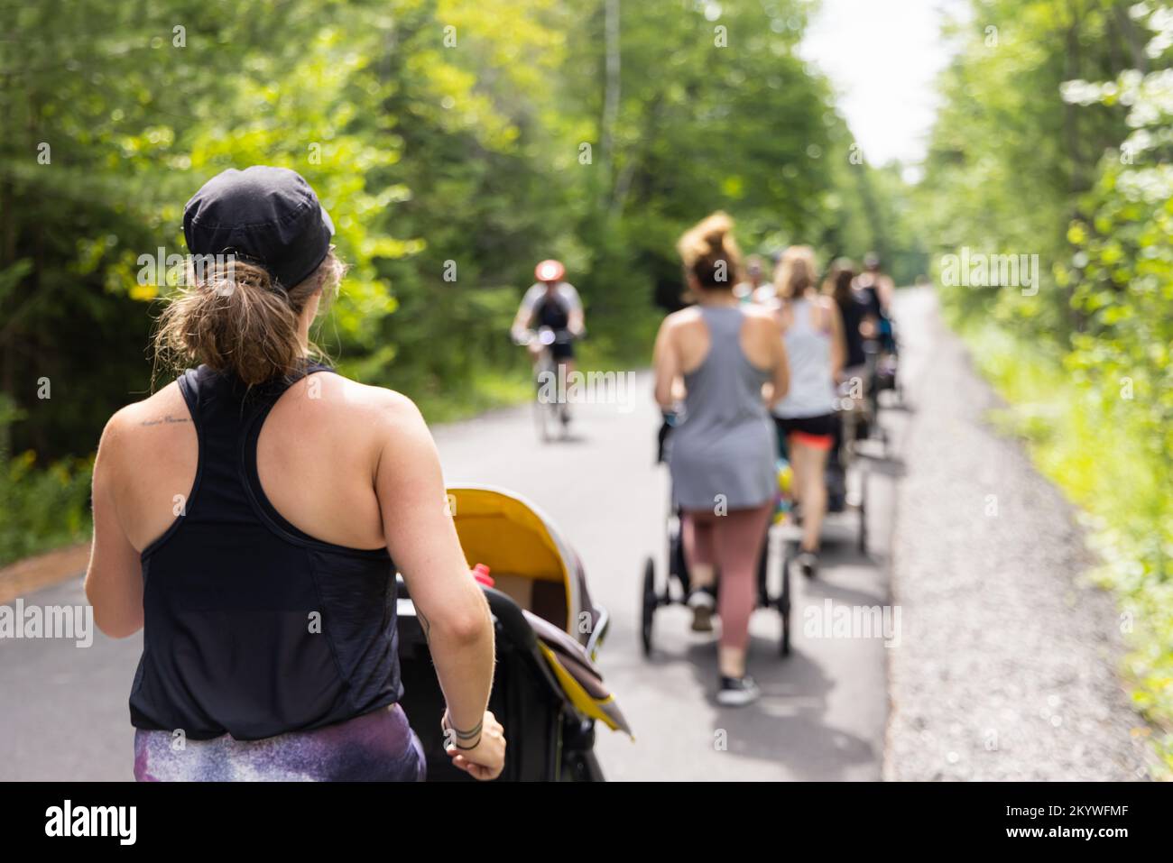 Foto vom Rücken einer Gruppe von Müttern, die an einer Outdoor-Fitnesssitzung teilnehmen, um nach der Geburt ihrer Babys ihre Muskeln wieder aufzubauen Stockfoto