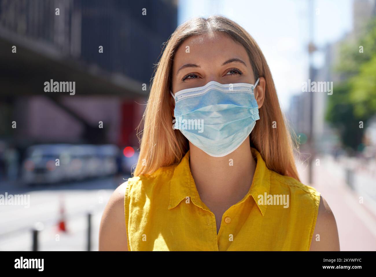 Verwendung der Maske. Junge Frau, die auf der Paulista Avenue mit einer Operationsmaske läuft, Sao Paulo, Brasilien. Stockfoto