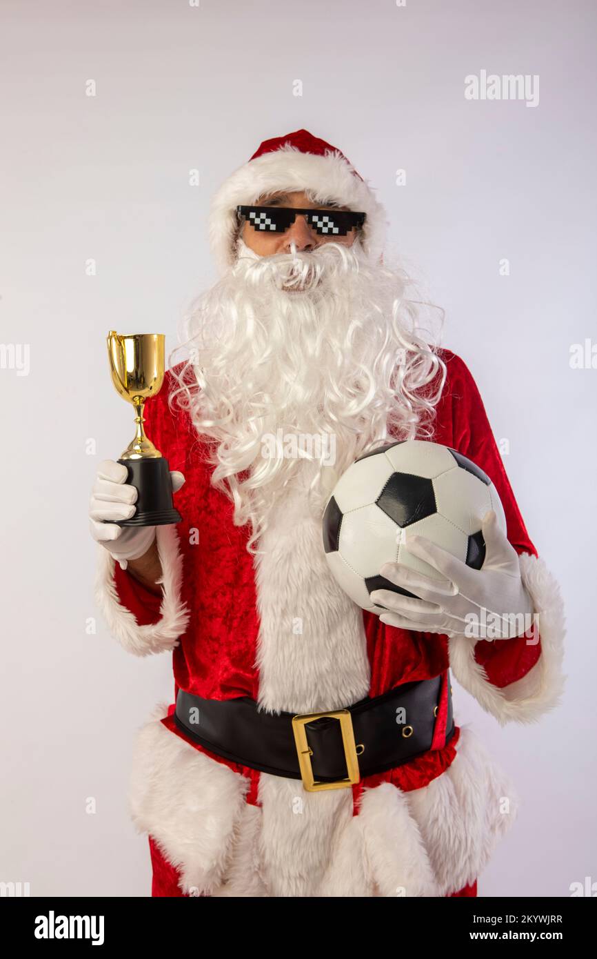 der weihnachtsmann mit Sonnenbrille, „Thug Life“-Fußball und einer Trophäe in der Hand auf weißem Hintergrund Stockfoto