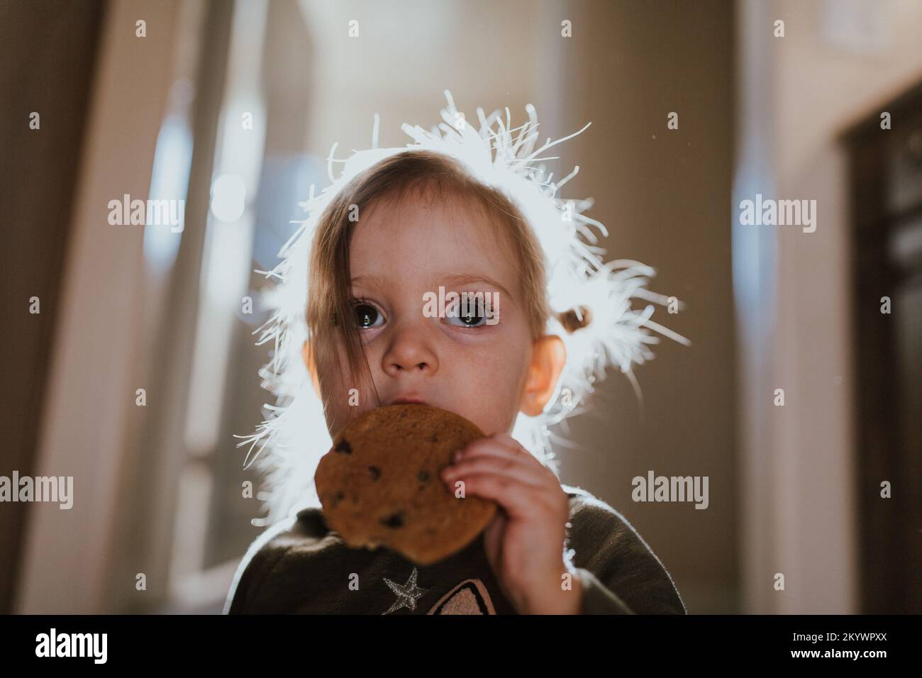 Trauriges kleines Mädchen, das einen Keks mit Tränen in den Augen isst Stockfoto