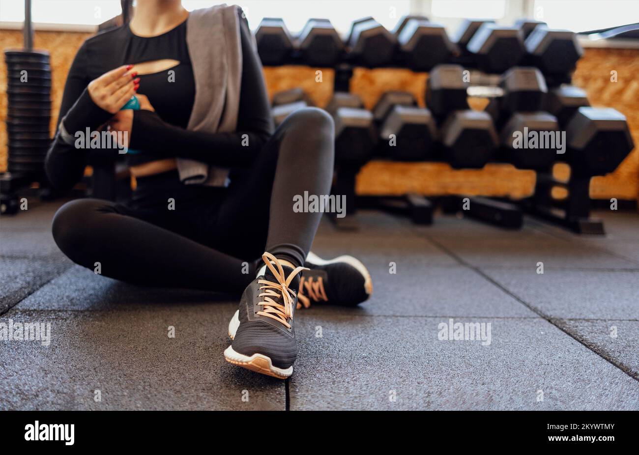 Frauen trainieren im Fitnessstudio Fitness brechen Entspannen Proteinshake Flasche halten nach dem Training Sport mit Kurzhantel und Kopfhörer Musikausrüstung hea Stockfoto