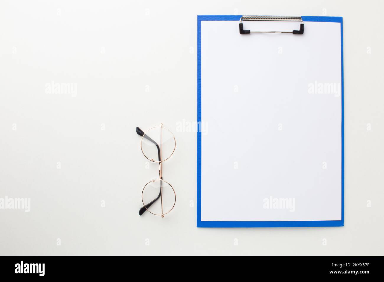 Leerer Aktenordner auf weißem Schreibtisch mit Brille zur Sichtprüfung. Draufsicht. Stockfoto