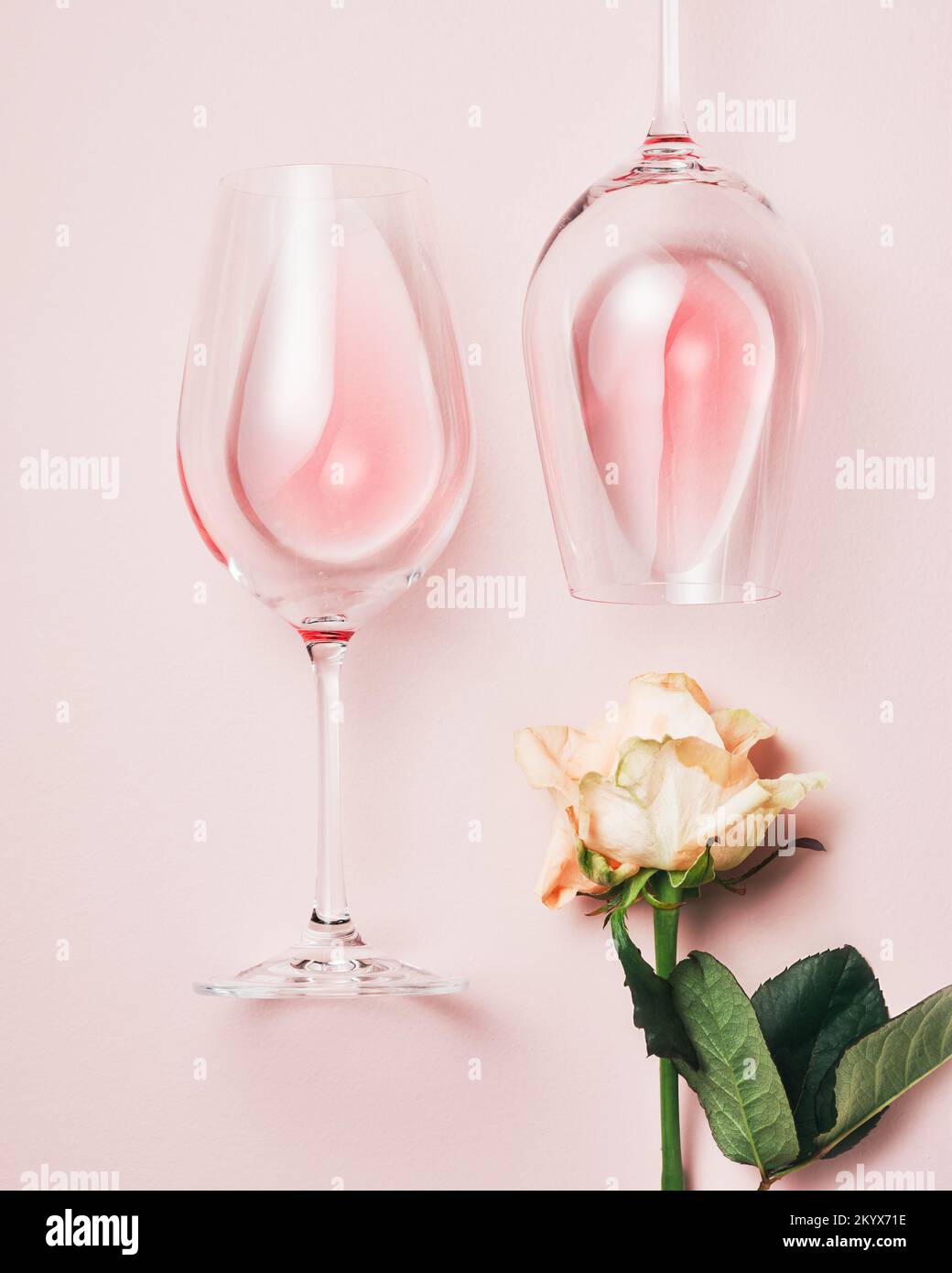 Zwei Gläser Rosenwein und eine Rosenblume auf einer rosafarbenen Oberfläche, Blick von oben. Stockfoto