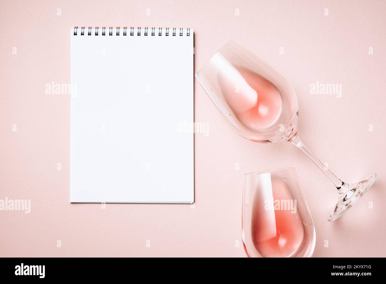 Zwei Gläser Rosenwein und ein Blatt Papier auf pinkfarbenem Hintergrund, Draufsicht. Stockfoto