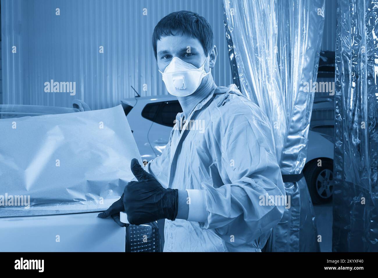 Mechaniker, der Auto vor dem Lackieren im Auto-Reparatur-Service bedeckt Stockfoto