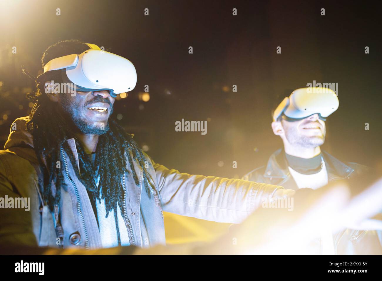 Zwei begeisterte Freunde, die VR-Brillen im Freien verwenden, erleben ein Virtual-Reality-Abenteuer Stockfoto